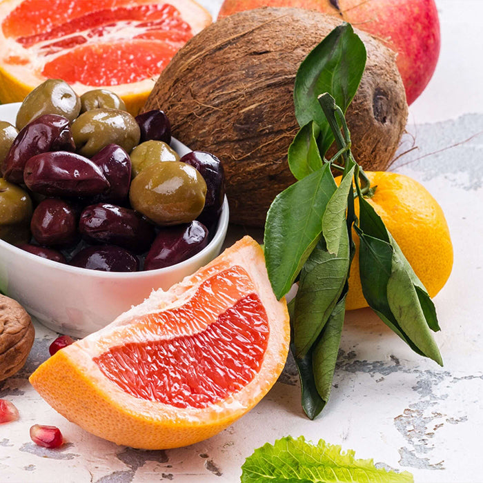 Assorted fruits and vegetables like oranges, pomegranate, and olives. Healthy food swaps for radiant skin!