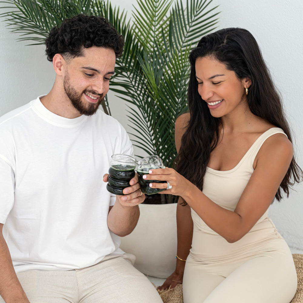 A happy couple enjoying a refreshing drink from a branded Rite bottle, dressed in a beige athletic outfit outdoors.