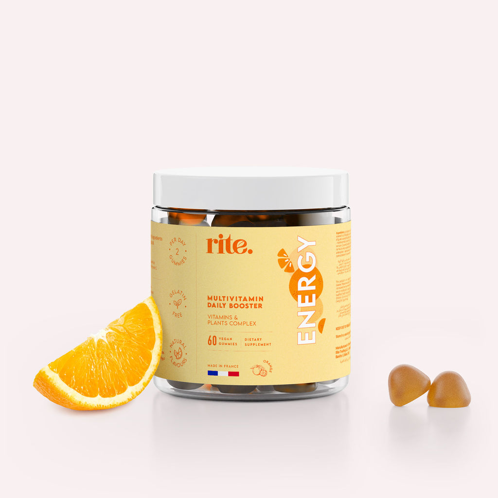 Jar of orange flavored vegan energy gummies next to a slice of orange