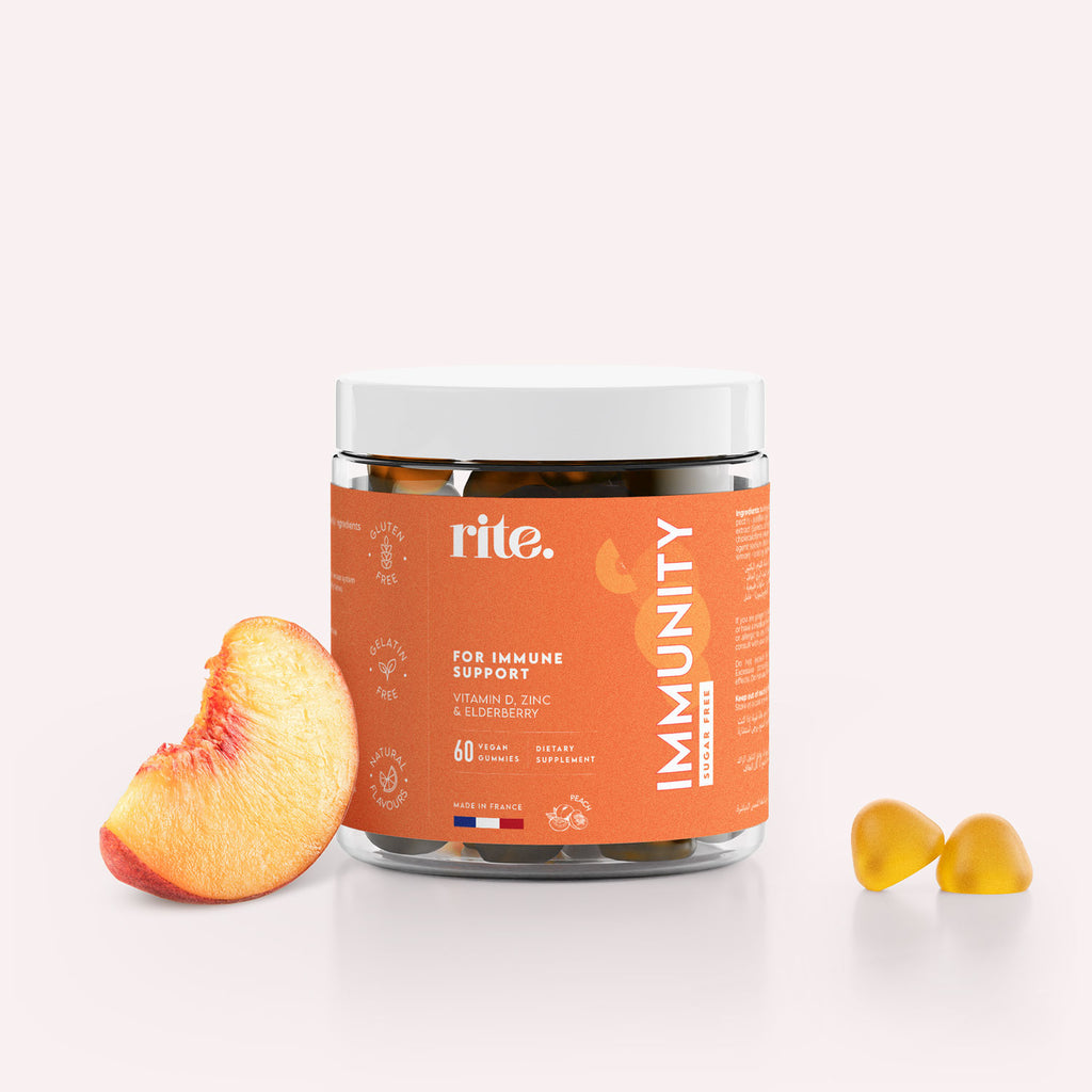 A jar of Rite IMMUNITY vitamin gummies sits on a light colored table next to a sliced peach. 