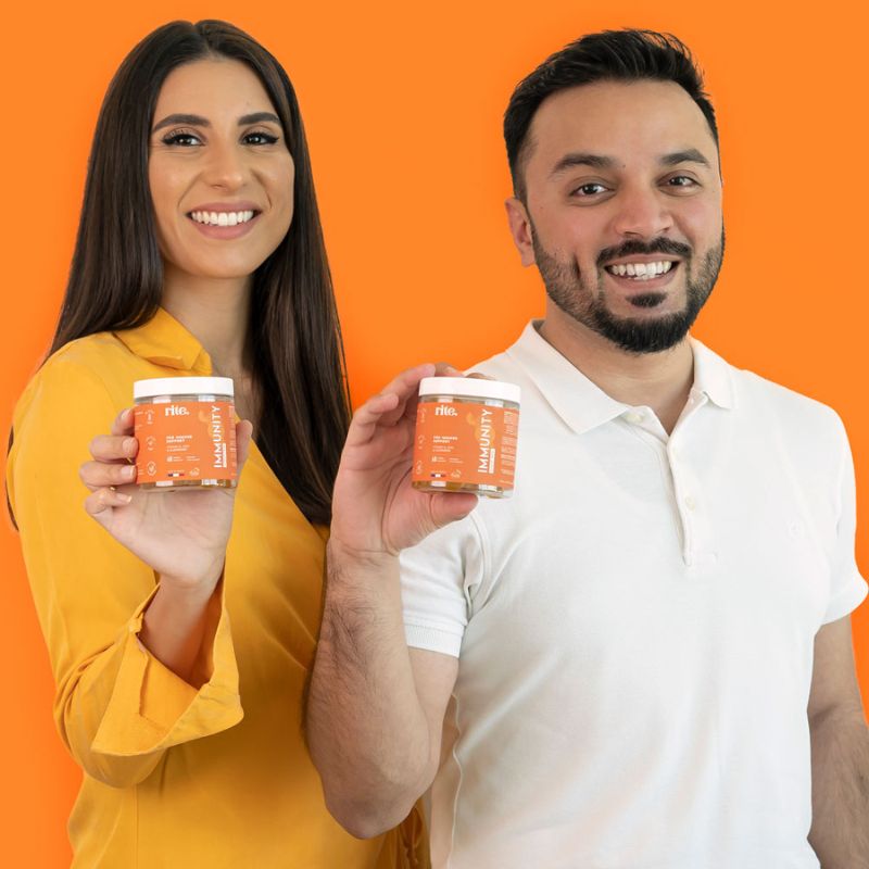 A man and woman holding up jars of vitamins labeled " IMMUNITY gummies"